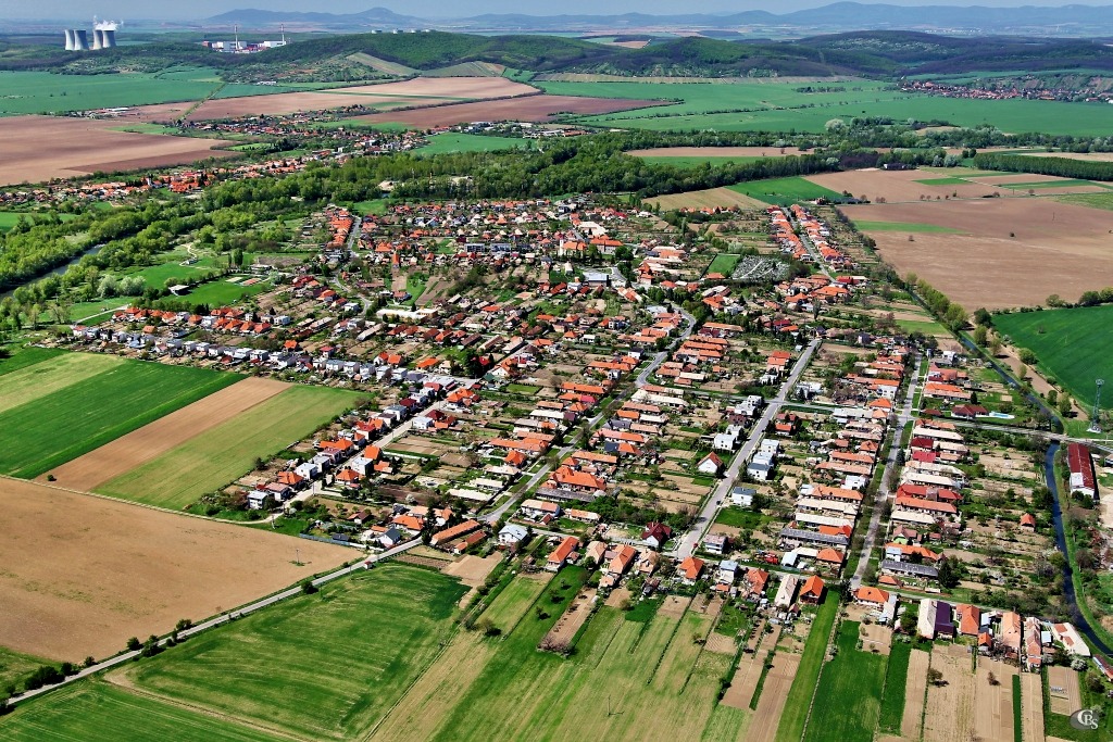 Pohľad na obec západným smerom v pozadí AE Mochovce (foto: archív autora) Pohľad na obec západným smerom v pozadí AE Mochovce (foto: archív autora)